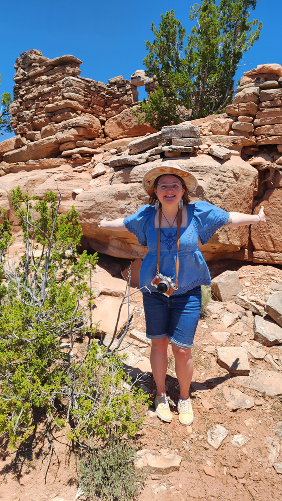 Visit Gallup, Zuni Pueblo. Carly stands in front of an ancient Zuni structure.